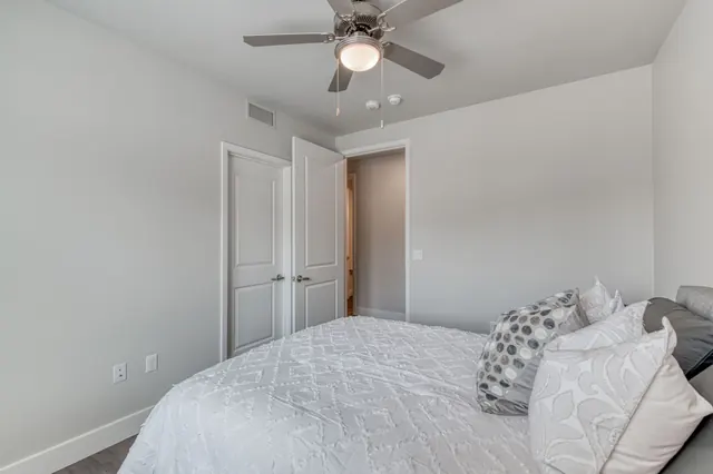 Bedroom with a ceiling fan, gray plank floors and an open closet