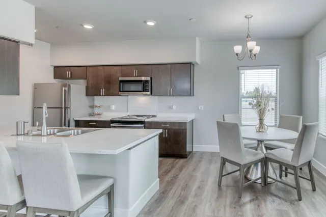 Kitchen with a quartz island, dark wood cabinets and a dining nook by the window