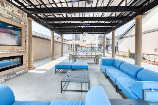 Covered outdoor lounge with an outdoor fireplace, TV and blue sectional seating
