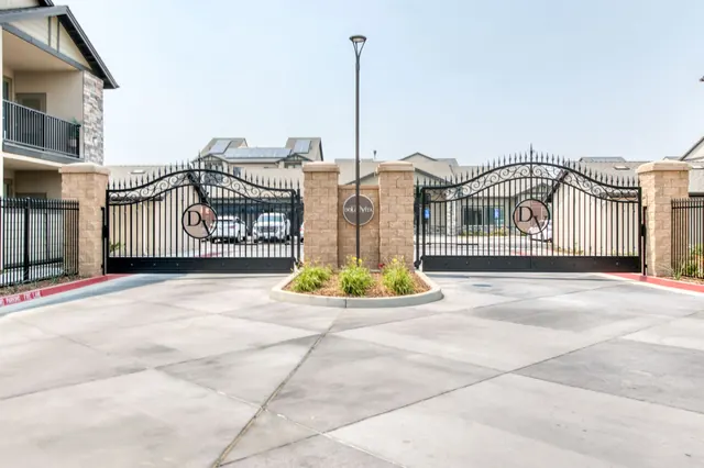 Wrought-iron entry gate with stone pillars and a landscaped island