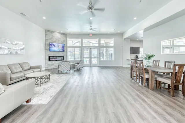 Clubhouse lounge with leather sofas, a stone fireplace wall and a long dining table